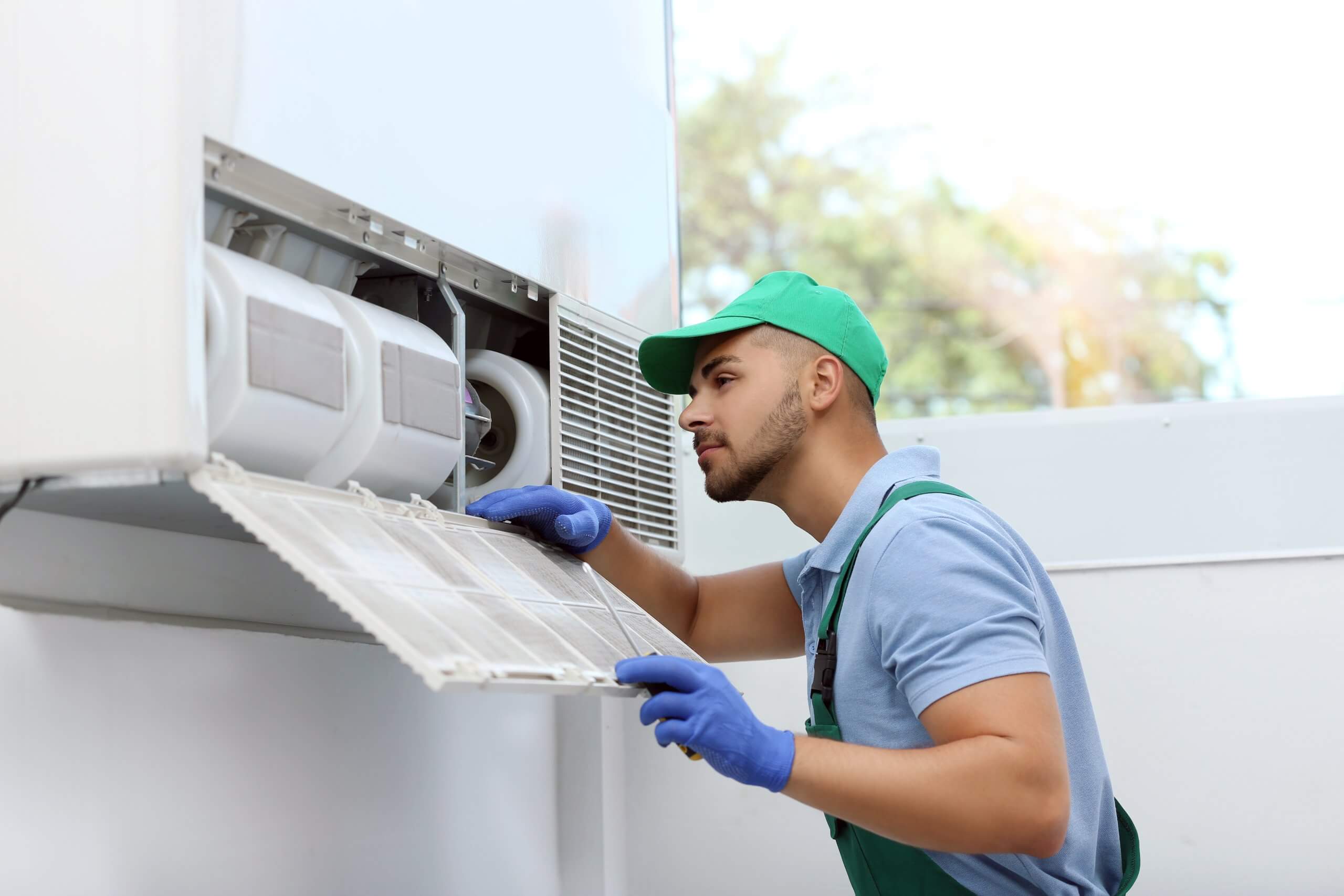 Professional technician maintaining modern air conditioner indoo Professional technician maintaining modern air conditioner indoors